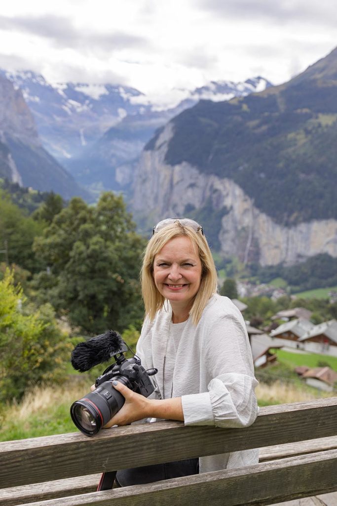 Picture of Emma Wilson, Swiss wedding videographer, posing with her video camera in front of the Swiss Alps in Wengen, Switzerland.