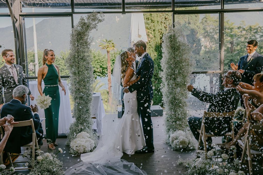 Bride and groom being showered by confetti during their wedding celebration at the Hotel Splendide Royal on Lake Lugano in Switzerland.