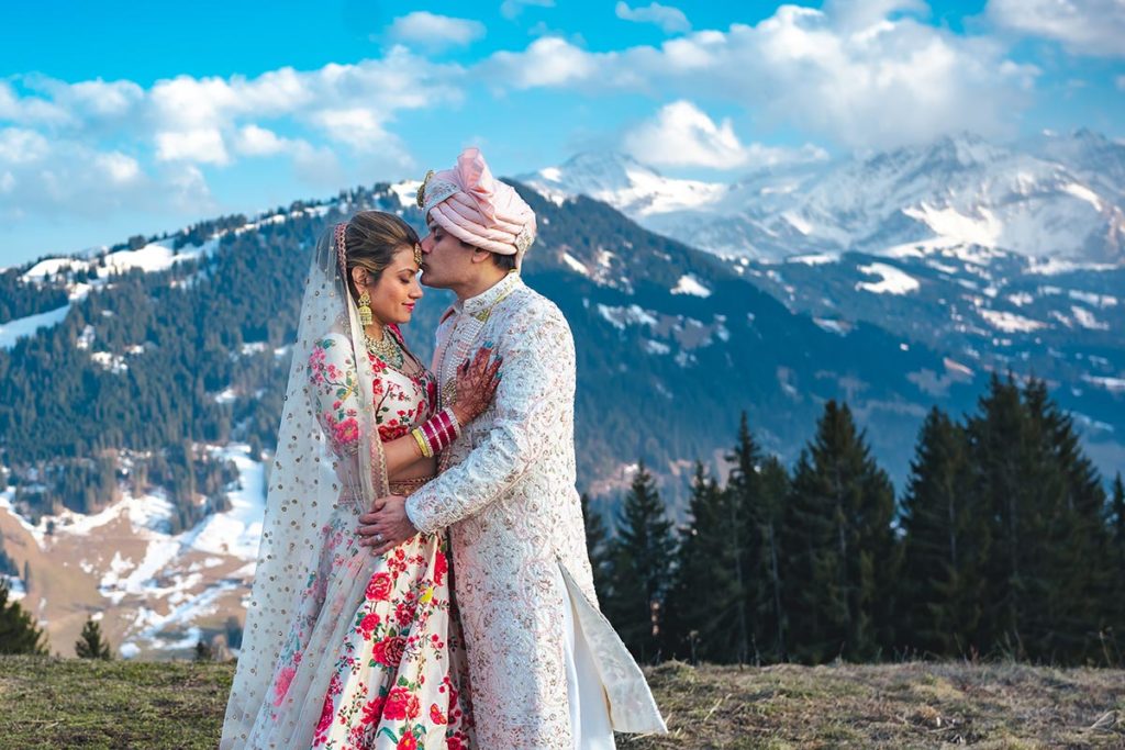 Newlywed Indian couple in traditional dress share a quiet moment together in the Swiss Alps in Gstaad, Switzerland after celebrating a mountaintop Indian wedding ceremony.