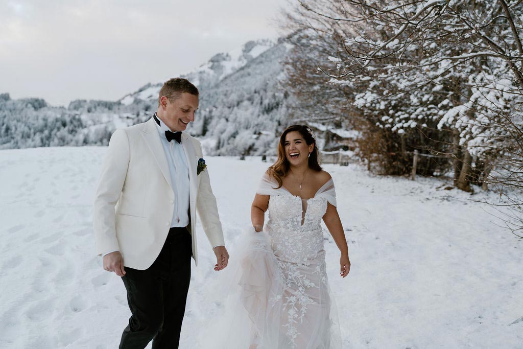 Couple laugh together while on a walk in a snowy landscape on their Swiss destination wedding at one of Switzerland’s best mountain wedding venues, The Huus Gstaad.