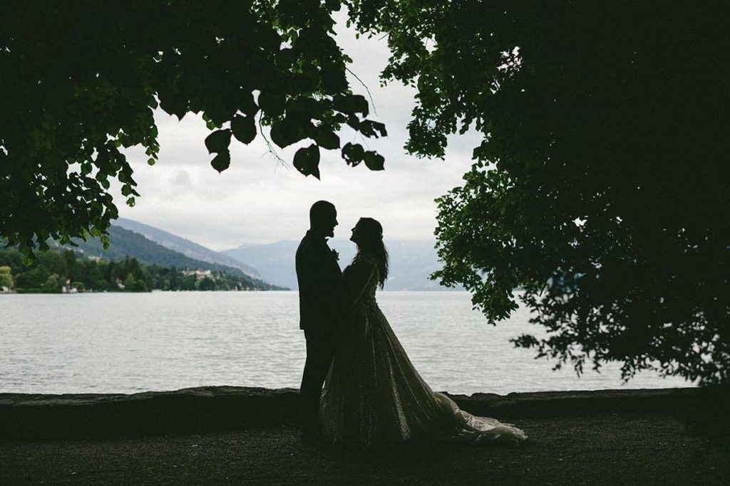 Silhouette image of a bride and groom standing in front of Lake Thun for their destination wedding at Schloss Schadau in Swizterland.