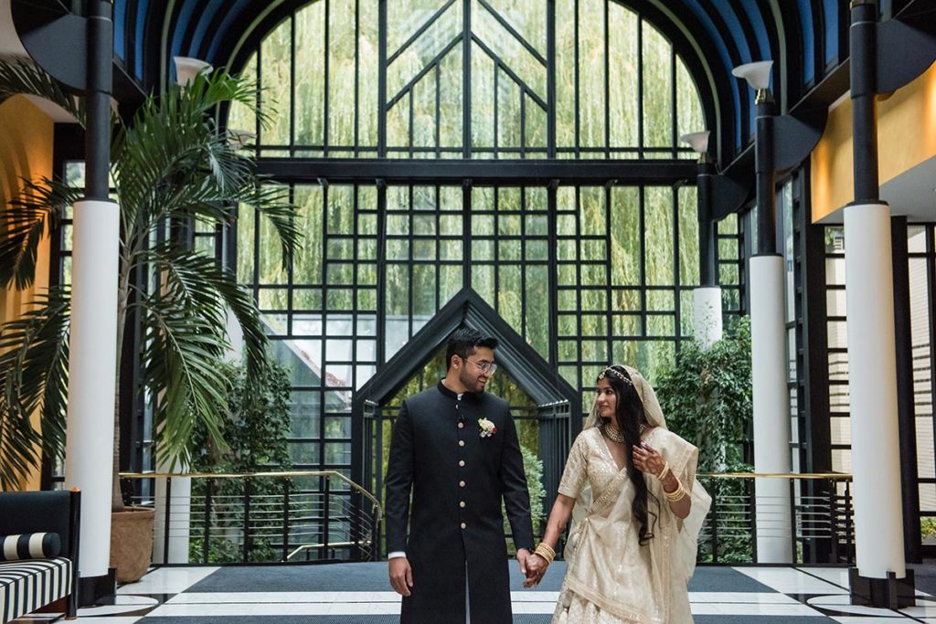 Indian bride and groom pose in front of a stunning geometric window at the Victoria Junfrau Hotel in Interlaken, Switzerland.