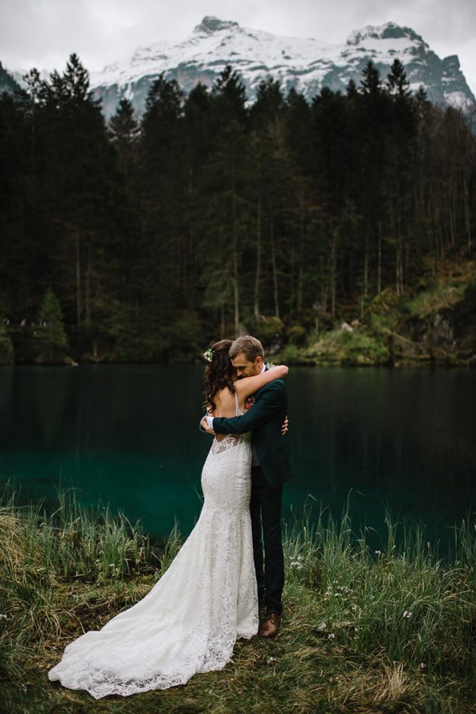 Wedding photo of an Australian couple embracing in front of Lake Blausee during their small wedding.