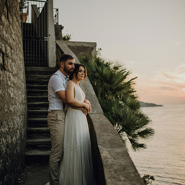 A bride and groom stand looking over the bay after their wedding ceremony on the Amalfi Coast, bay of Naples, Italy