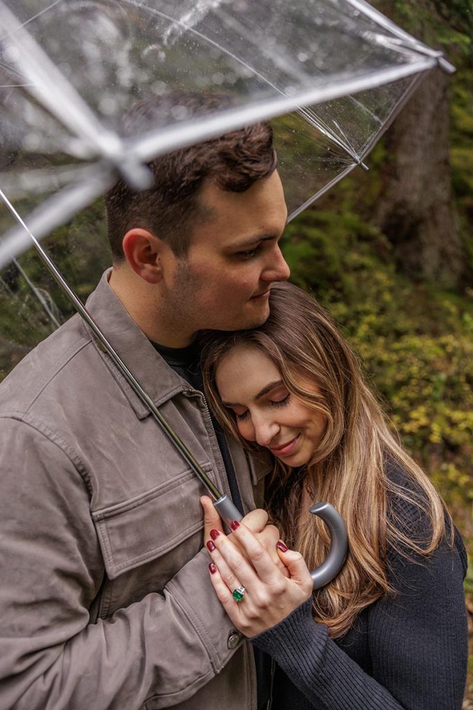 A couple embrace under an umbrella after getting engaged to be married in Switzerland.