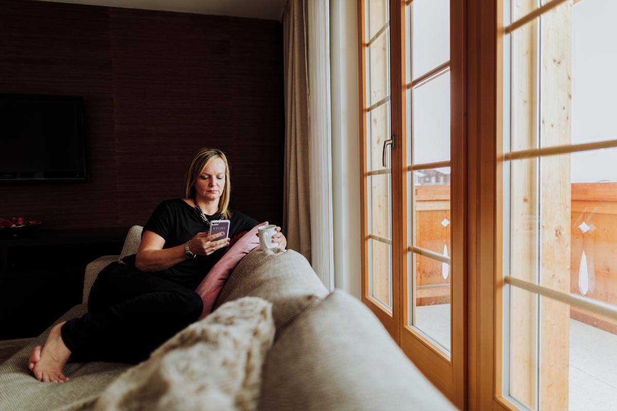 Emma Wilson, Swiss wedding videographer, sitting on a sofa looking at her mobile phone