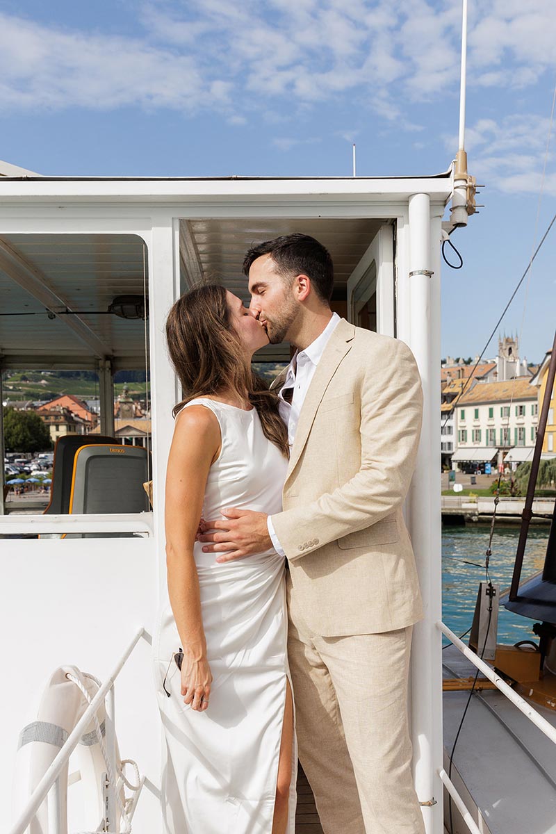 Un couple de mariés s'embrasse sur un bateau sur le lac Léman lors de leur mariage au Fairmont Montreux.