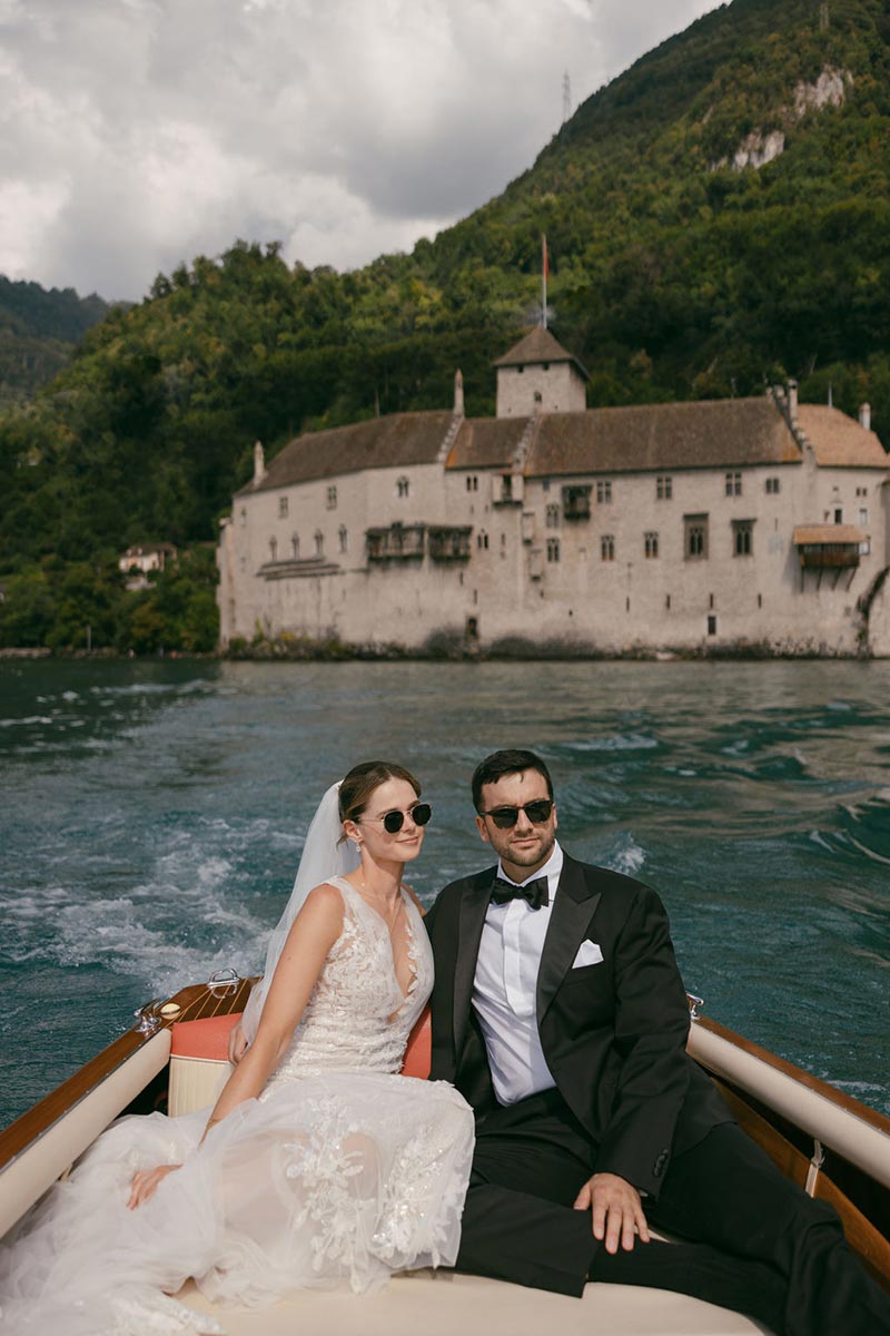 Un couple de mariés se détend dans un hors-bord en bois, portant des lunettes de soleil, lors de leur mariage au Montreux Palace en Suisse.